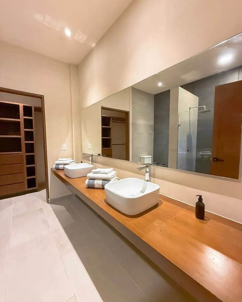 Baño con lavabo sobre cubierta de madera y regadera de cristal