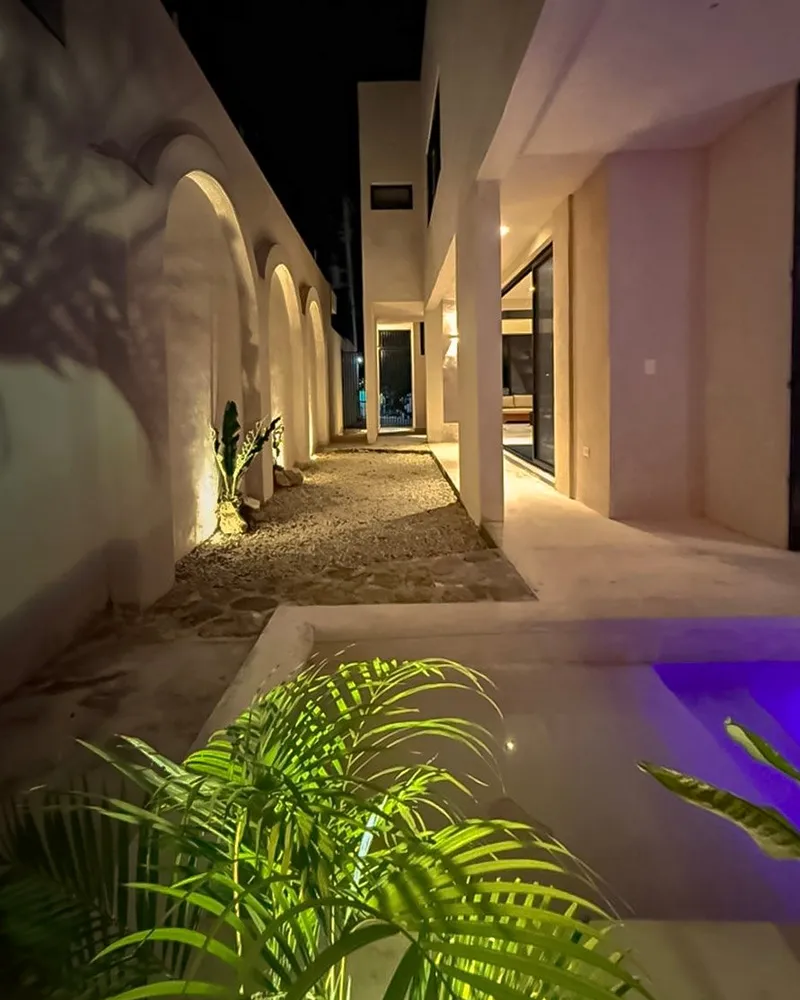 Allée extérieure de nuit, avec arches éclairées et piscine