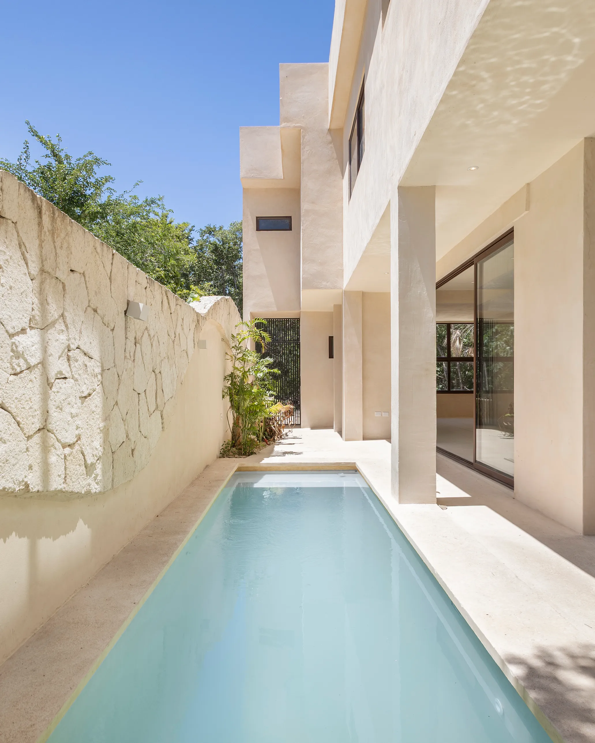 Piscine au rez-de-chaussée de la Villa Quetzal, le long d’un mur de pierre avec jardin