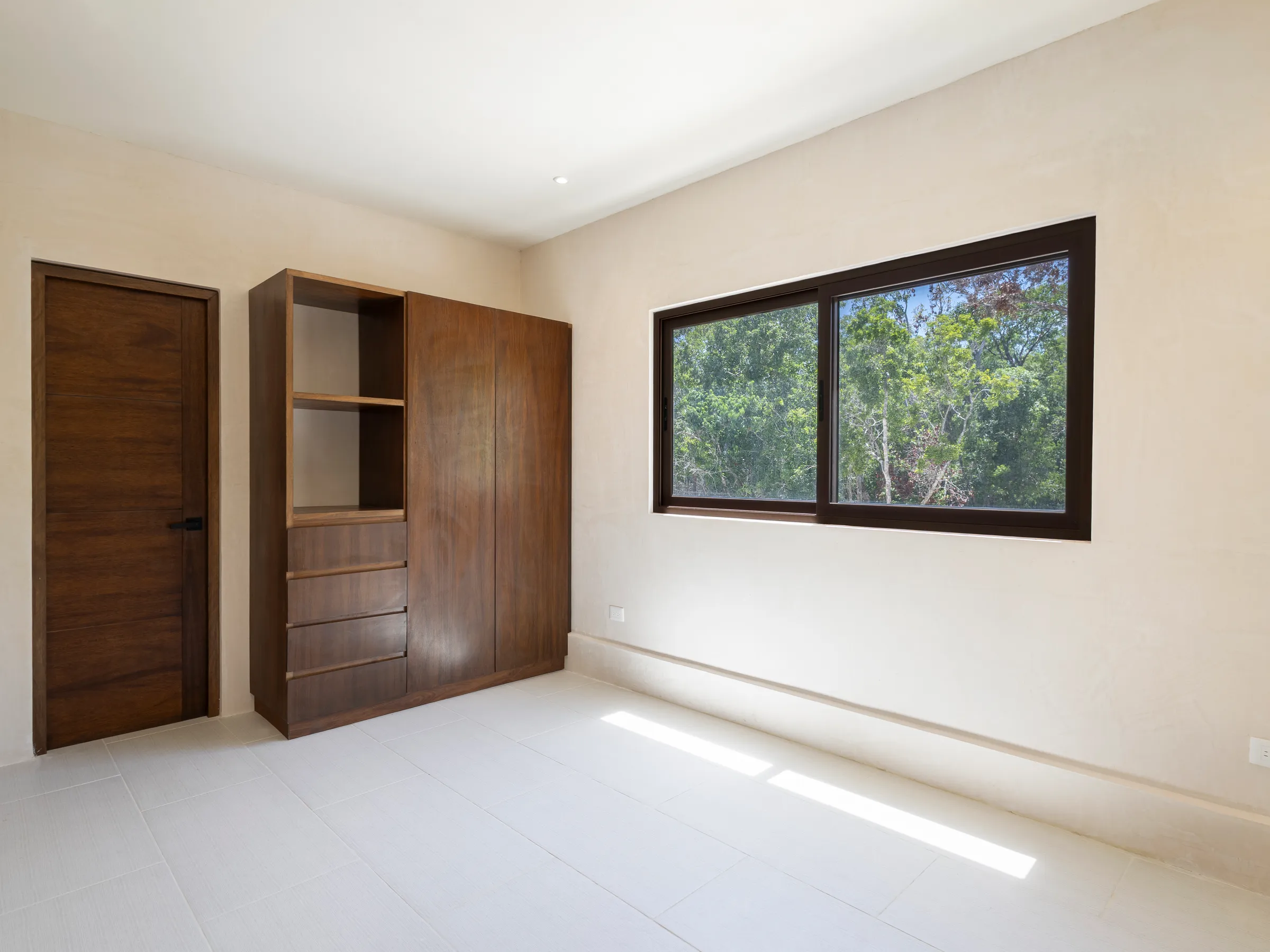Chambre de la Villa Quetzal avec placard en bois et fenêtre sur la végétation