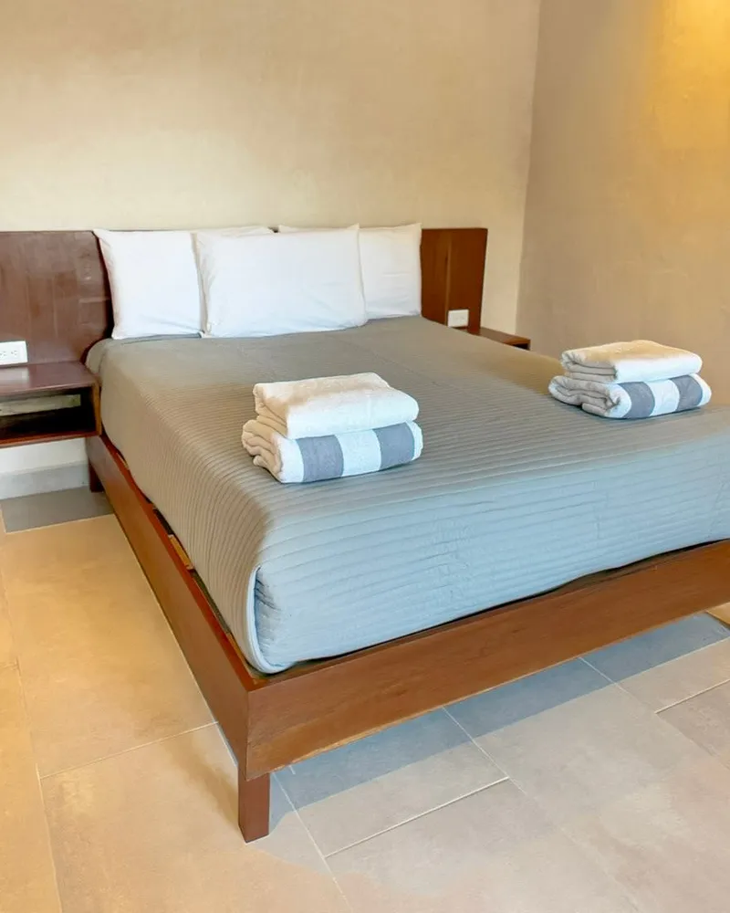 Cama con toallas dobladas y buró de madera